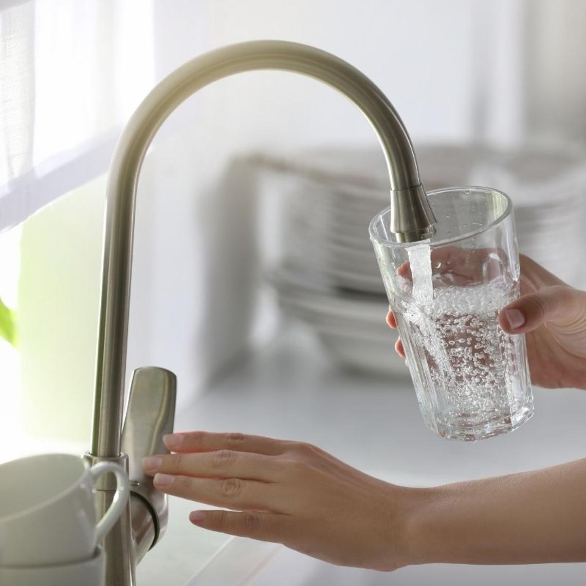 woman turning on tap in kitchen