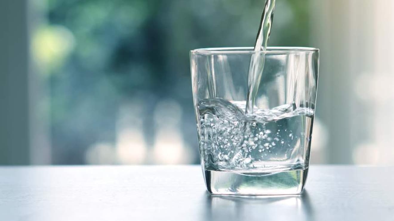 Tap water pouring into in glass against a blurred background