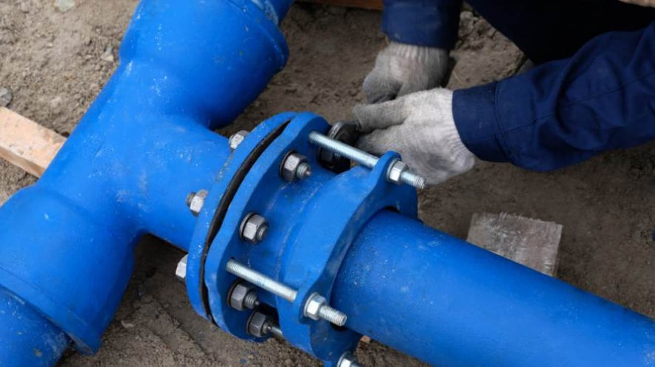 engineer bolting two water main supply pipes together