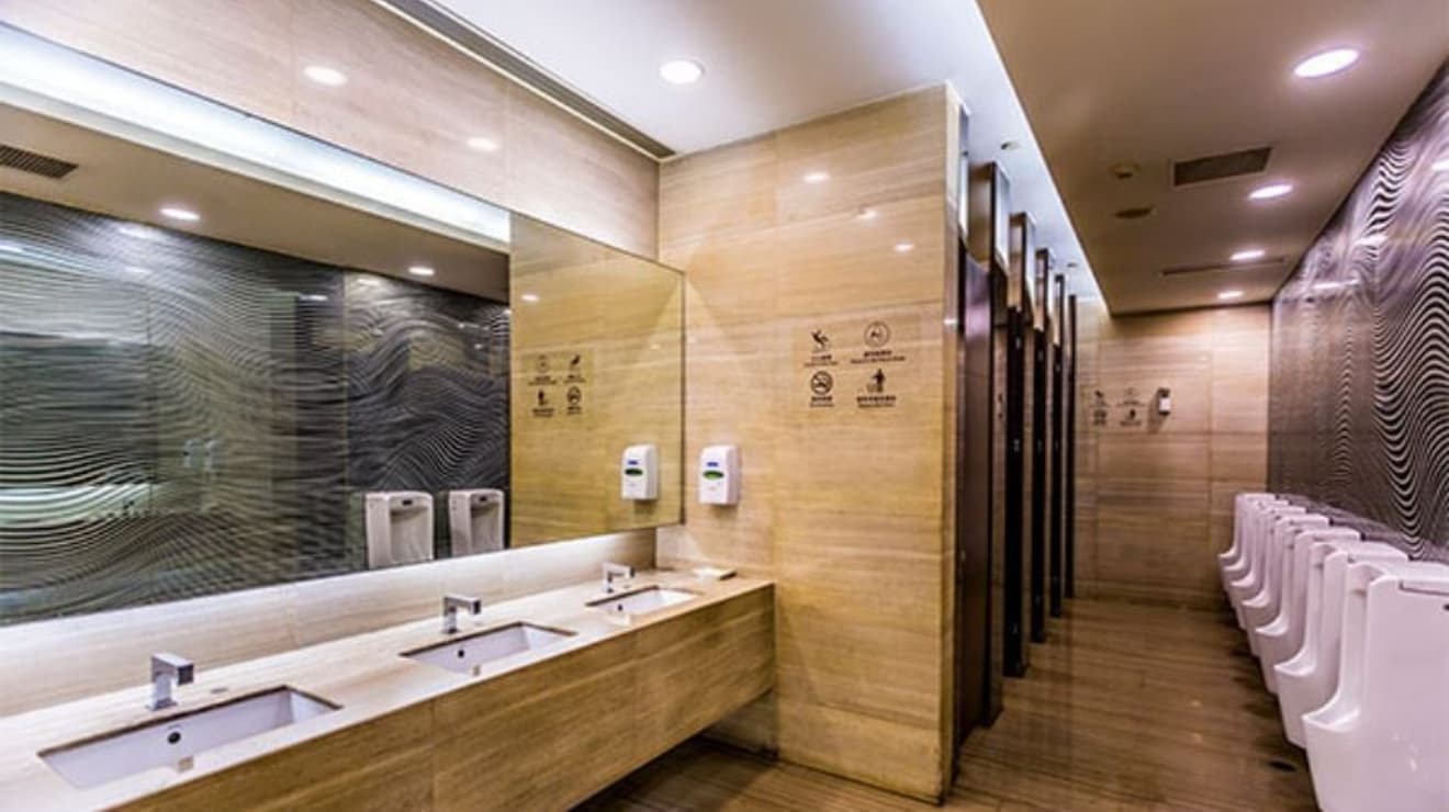 Three bathroom sinks and cubicles in a bathroom